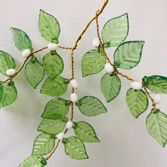 Decorative green leaf garland with white beads on a light background