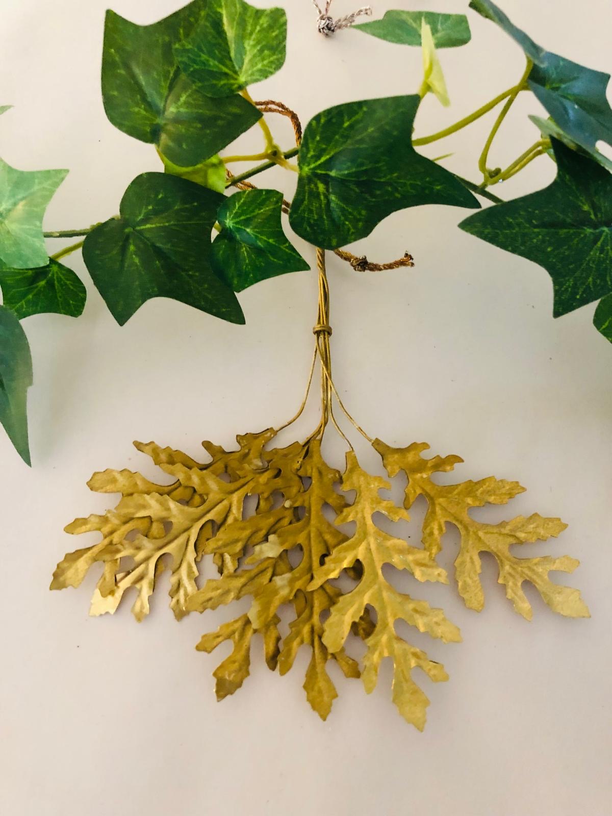 Artificial green ivy leaves with gold leaf accents on a white background