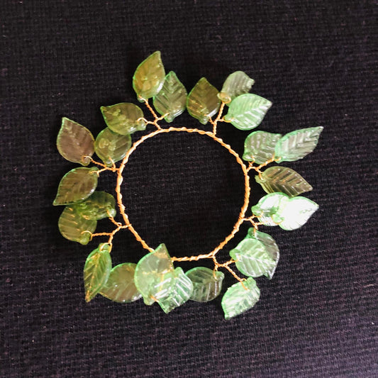 Decorative wreath with green leaf-like elements on a black background