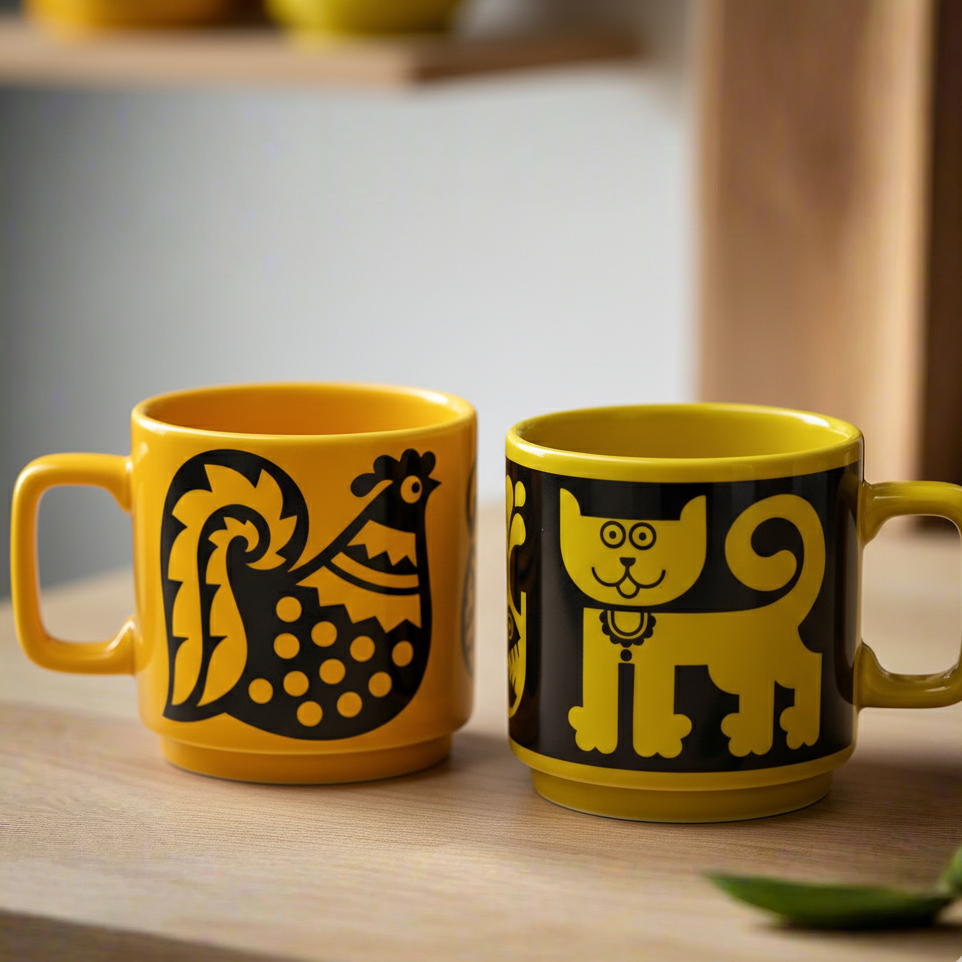 Two yellow mugs with black animal illustrations on a wooden surface.