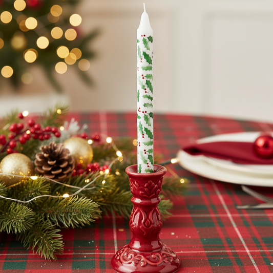 Decorative candle in a red holder on a Christmas-themed table setting with lights and greenery.