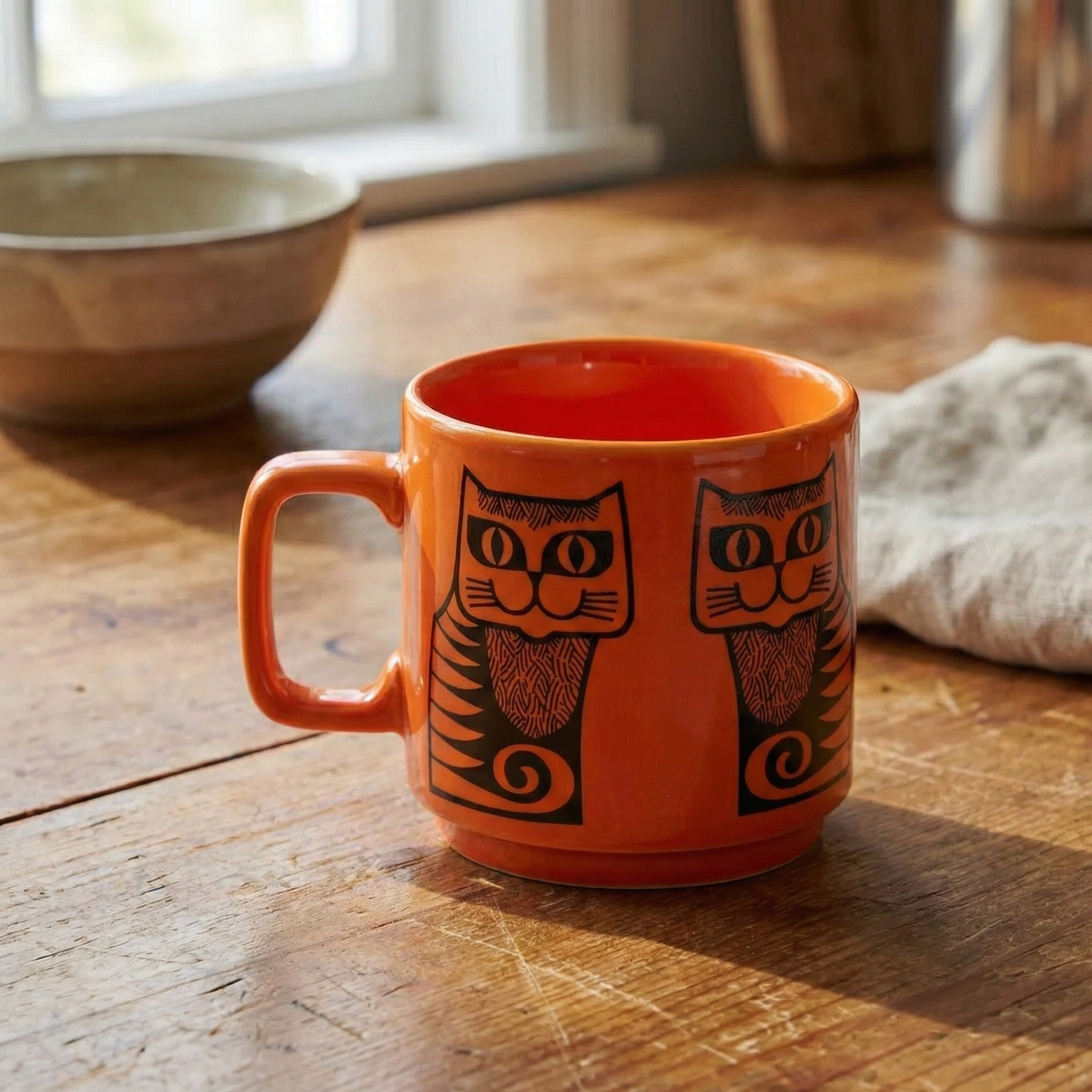 Orange mug with cat design on a wooden surface