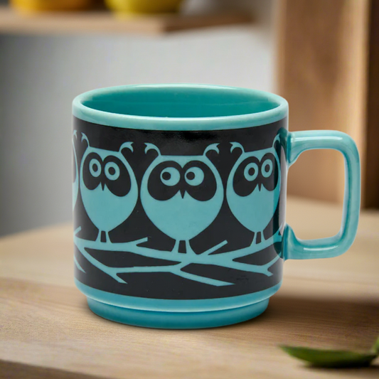 Teal mug with owl design on a wooden surface