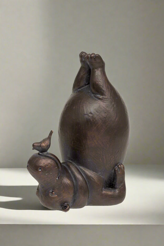 Bronze sculpture of a hippo with a bird on its back against a white background